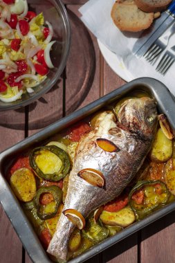 Lezzetli fırında pişirilmiş, otlu ve limonlu balık, metal fırın tepsisinde. Seçici odaklanma. Kapat..