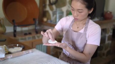 Geleneksel Çin jiaozi 'sini hazırlarken günlük kıyafetleri ve önlükleri et ile dolduran kadın.