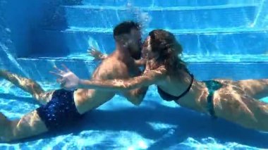 Mayo giyen, su altında yüzen ve öpüşen, yaz tatilinde birlikte vakit geçirirken kucaklaşan pozitif bir çiftin yan görüntüsü.
