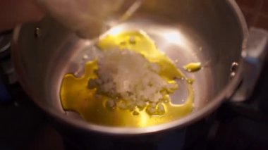 Yüzsüz aşçının tavaya doğranmış sarımsak koyması ve mutfakta yemek pişirmesi.