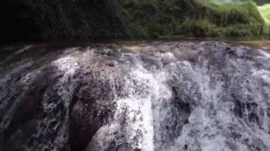 Güneşli bir günde ağaçların altındaki kayaların üzerinden akan suyun altından.