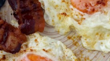 Lezzetli, güneşli yumurtalar ve kızarmış pastırma dilimleri.