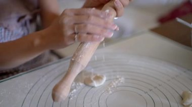 Mutfakta etli börek hazırlarken önlüklü isimsiz bir kadının masanın üstünde hamuru yuvarlaması.