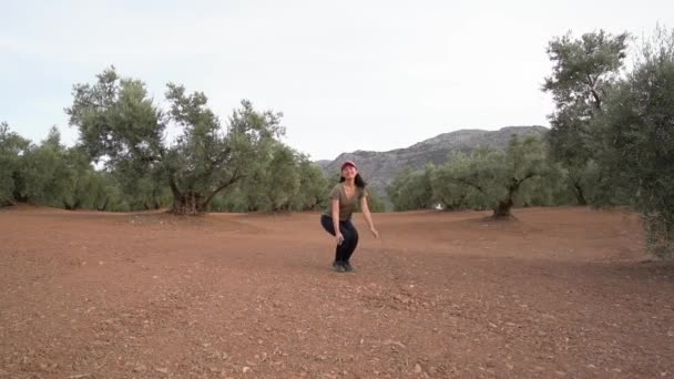 Zengin Yeşil Zeytin Ağaçlarıyla Fidanlıkta Zıplarken Akıllı Telefonlu Asyalı Kadın — Stok video