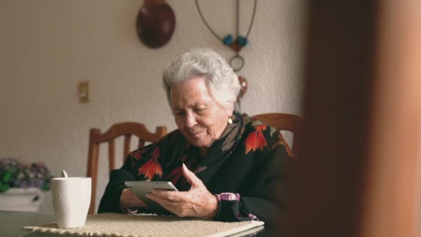 Uśmiechnięta Starsza Kobieta Ciepłych Ubraniach Siedząca Przy Stole Tabletką Filiżanką — Wideo stockowe