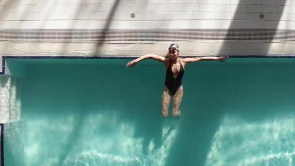 年轻美丽的女人穿着黑色的泳衣 在游泳池边 面朝上浮在水面上 去潜水 — 图库视频影像