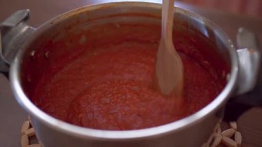 İsimsiz şef taze karışık domatesleri tencereye dolduruyor ve mutfaktaki fırında marinara sosu hazırlıyor.