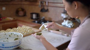 Geleneksel Çin jiaozi 'sini hazırlarken günlük kıyafetleri ve önlükleri et ile dolduran kadın.