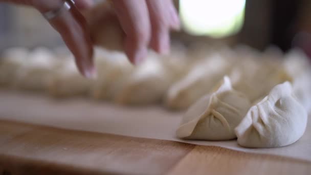 台所の列に木製のテーブルで提供される詰め物の調理されていないチャオジー餃子の閉鎖 — ストック動画
