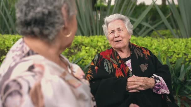 Stara Kobieta Uśmiecha Się Siedząc Przy Stole Egzotycznym Podwórku Dłońmi — Wideo stockowe