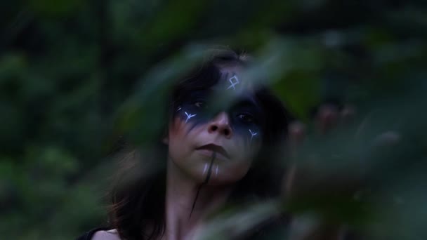 ゆっくりとした動きで暗い森の中で木の枝に触れる塗装顔と優雅な魔女 — ストック動画