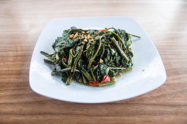 Stir fried water spinach with garlic and pepper on white plate