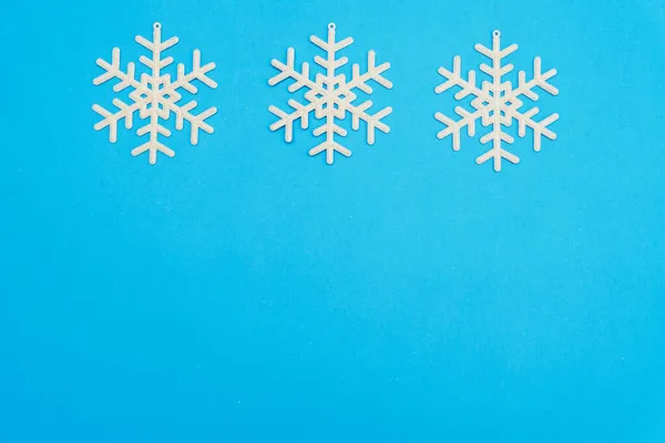 La composition de Noël, un groupe de flocons de neige blancs brillants sur un fond bleu en haut, copier l'espace. Festive, concept du Nouvel An. Style minimum. Vue du dessus — Photo