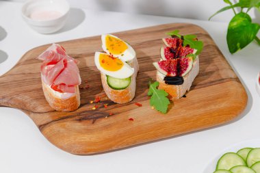 Kahvaltıda krem peynirli, jambonlu, incirli, yumurtalı, domatesli, salatalıklı, roka ve balzamik sirkeli bruschetta hazırlıyorum. Ya da krem peynirli, jambonlu, incirli ve yumurtalı. Kaybedeceksin. Yüksek kalite fotoğraf