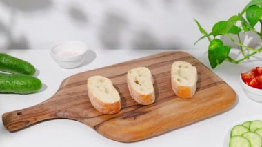 Kahvaltı için krem peynirli, jambonlu, incirli, yumurtalı, domatesli, salatalıklı, roka ve balzamik sirkeli bruschetta yapıyorum. Beyaz mutfakta hareket animasyonunu durdur. 