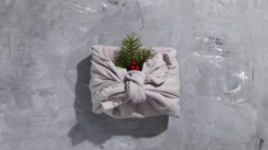 Geleneksel Japon furoshiki tarzı sıfır atık hediye paketi gri arka planda. Plastiksiz, Noel için el yapımı hediye paketi ve diğer şenlikli etkinlikler için. Hareketi durdur.