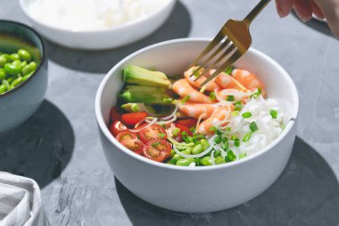 Kırmızı karides, pirinç, domates ve edamame fasulyelerini gri arka plandaki beyaz kaseye koy. - Yakın çekim. Yüksek kalite fotoğraf