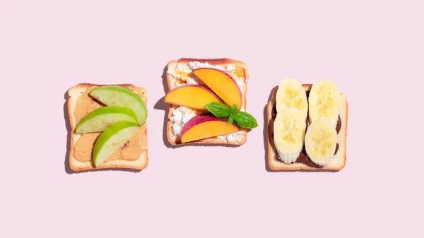 Set of toasted bread with peach, apple and banana on pink background. High quality photo