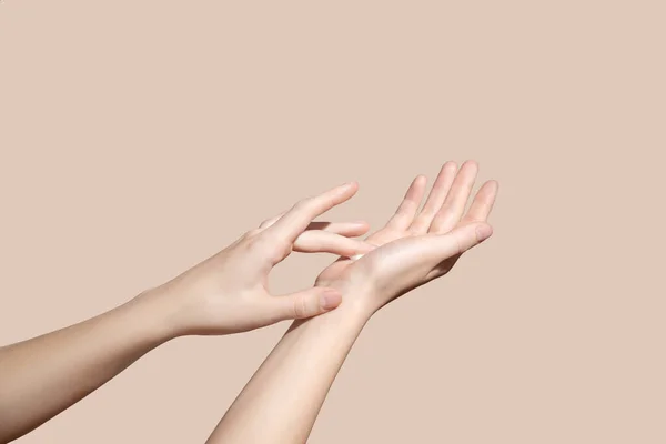 Hands Applying Cream, Lotion on a beige background. Spa and Manicure concept. Soft skin, skincare concept. High quality photo