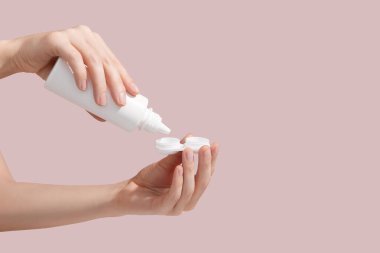 Closeup female hands are holding container for optical contact lens. Young woman is pouring contact lens solution liquid for disinfecting and cleaning. Ophthalmic diseases and treatment concept. High quality photo