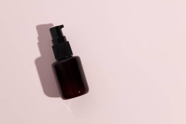 Black bottle of serum on pink background. Mockup. High quality photo