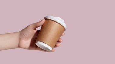 Elinde pembe arka planda bir kahve fincanı tutan bir kadın resmi. Yüksek kalite fotoğraf