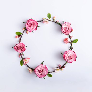 Açık gri arkaplanda kırmızı güllerden yapılmış yuvarlak çerçeve.