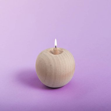 Mor arka planda yanan bir mum gibi ahşap bir elma. Asgari soyut yaz konsepti. Isometric kare düzeni.