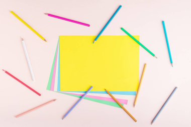Açık pembe arka planda pastel renklerde çok renkli kalem ve kağıtların yaratıcı deseni. Okul konseptine geri dönelim. Kopyalama alanı olan dikdörtgen bir düzen. Üst manzara, düz uzanma.