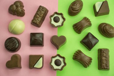 Çeşitli çikolatalı pralinaların en iyi görüntüsü. Pembe ve yeşil renklerle karışık arkaplan.