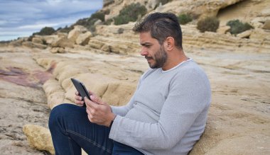 Açık havada dijital tablette okuyan bir adam.