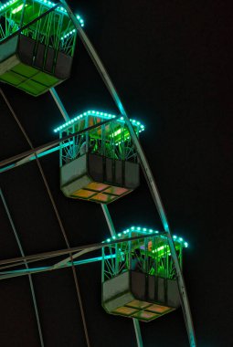 Theme park. Detail of several Ferris wheel cubes at night. Neon lights. Celebrations and events. People enjoying the night after the pandemic.