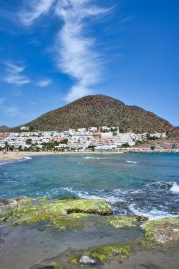 SAN JOSE, ALMERIA, İSPA: 25 Mayıs 2021: Güneşli bir günde, İspanya 'nın Almerya kentindeki Cabo de Gata' da çok ünlü bir turizm merkezi olan San Jose şehrinin panoramik manzarası. Dağ ve beyaz evler