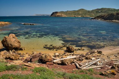 Cala Morts güneşli bir günde, bu koy Cami de Cavalls rotasının bir parçasıdır. Bir sürü bitki örtüsü olan deniz ve dağ manzarası