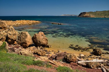 Cala Morts güneşli bir günde, bu koy Cami de Cavalls rotasının bir parçasıdır. Bir sürü bitki örtüsü olan deniz ve dağ manzarası