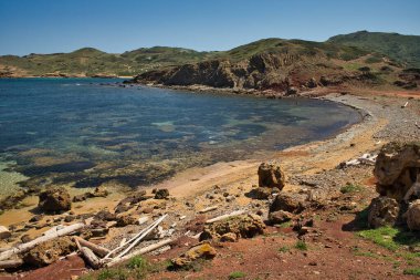 Cala Morts güneşli bir günde, bu koy Cami de Cavalls rotasının bir parçasıdır. Bir sürü bitki örtüsü olan deniz ve dağ manzarası