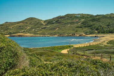 Cala Binimela, güneşli bir günde Balear Adaları 'nda Cami de Cavalls rotasında. Deniz ve dağ manzarası. Turkuaz sular. Meşhur bir yer. Seyahat konsepti. Bir sürü bitki örtüsüyle.