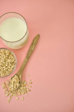 Oat flakes and oat drink in glass jars on pastel pink background. Healthy lifestyle and diet concept. Top view. space for text.