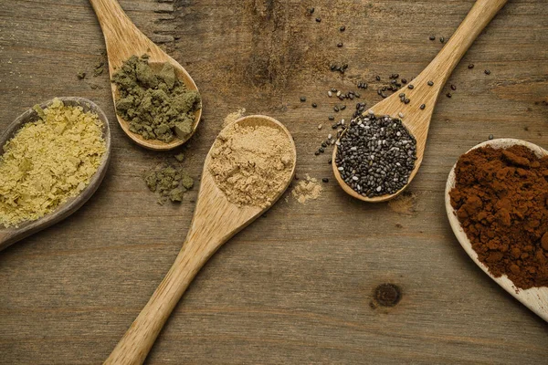 Tahta kaşıklar üzerinde süper yiyeceklerin kırsal bileşimi. Maca, Chia, Hemp Protein, saf kakao ve besin maya, hepsi vitamin ve omega-3 kaynağı. Sağlıklı yaşam tarzı ve diyet konsepti. Üst görünüm