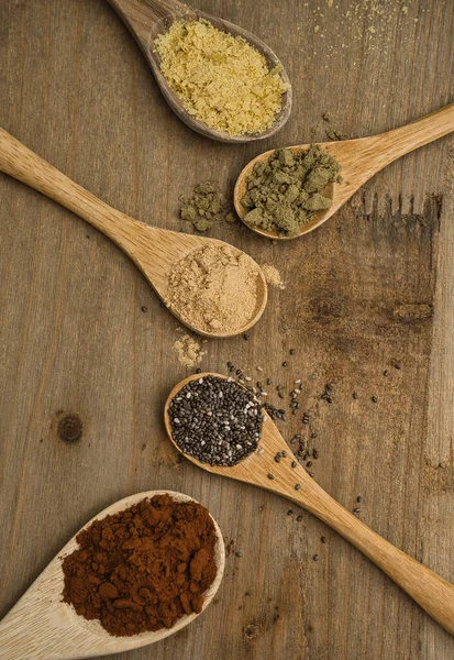 Tahta kaşıklar üzerinde süper yiyeceklerin kırsal bileşimi. Maca, Chia, Hemp Protein, saf kakao ve besin maya, hepsi vitamin ve omega-3 kaynağı. Sağlıklı yaşam tarzı ve diyet konsepti. Üst görünüm