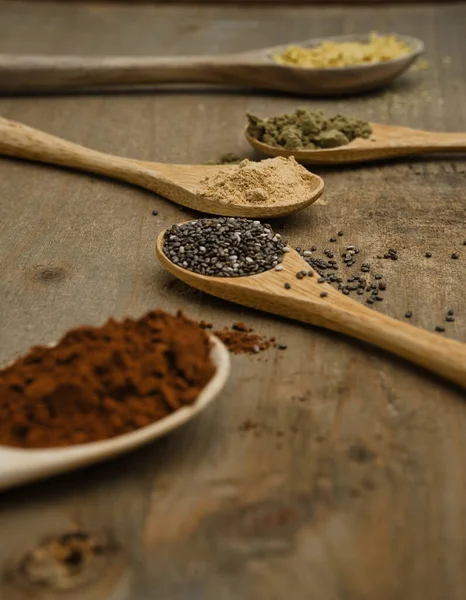 Tahta kaşıklar üzerinde süper yiyeceklerin kırsal bileşimi. Maca, Chia, Hemp Protein, saf kakao ve besin maya, hepsi vitamin ve omega-3 kaynağı. Sağlıklı yaşam tarzı ve diyet konsepti. Yan görünüm