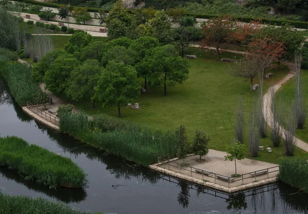 Bulutlu bir yaz gününde, büyük şehrin merkezindeki parkın panoramik manzarası. Ortasında bir göl ve yeşil ağaçlar var. Yağmurun nemli atmosferinde. Açık hava spor alanı
