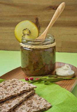 Krem peynirli ve Kivi reçelli çavdar ekmekli tost. Kırsal ve ahşap arka planda sağlıklı yiyecekler, turunçgiller ve vitaminler