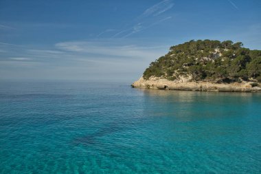 Denizin ortasındaki bir adanın panoramik görüntüsü, mavi gökyüzü olan güneşli bir günde deniz kenarında geziler için ilham verici bir manzara. Metin için alanı kopyala.