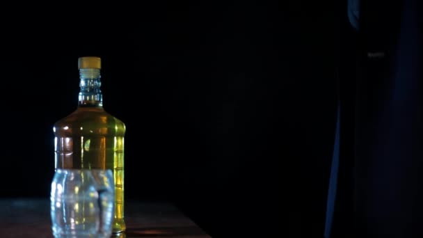 一个酒吧的男人拿出一瓶酒和一个空杯子放在桌上 并在桌上放上戏剧性的灯光 — 图库视频影像