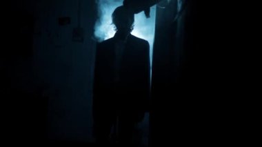 Dramatik ışıkta yürüyen takım elbiseli bir adamın sinematik görüntüleri ve etrafında biraz sis. Yürüyen bir adamın karanlık görüntüsü. Yüksek çözünürlüklü görüntüler.