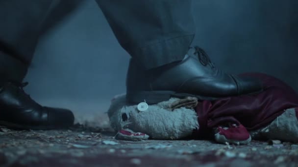 一个男人撞倒一只泰迪熊的特写镜头 在戏剧性的光线下踩着泰迪熊走路的人 — 图库视频影像