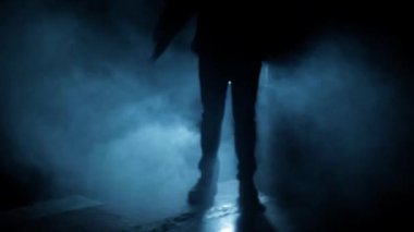 Cinematic shot of a professional killer in long court with a handgun in dramatic light, and smoke.