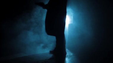 Cinematic shot of a professional killer in long court with a handgun in dramatic light, and smoke.
