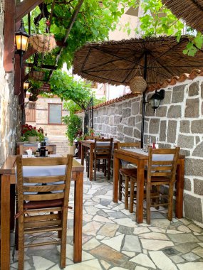 Küçük, rahat bir kafe, üzümlere sarılı, küçük ahşap masa, taş duvarlar, tatil, yaz
